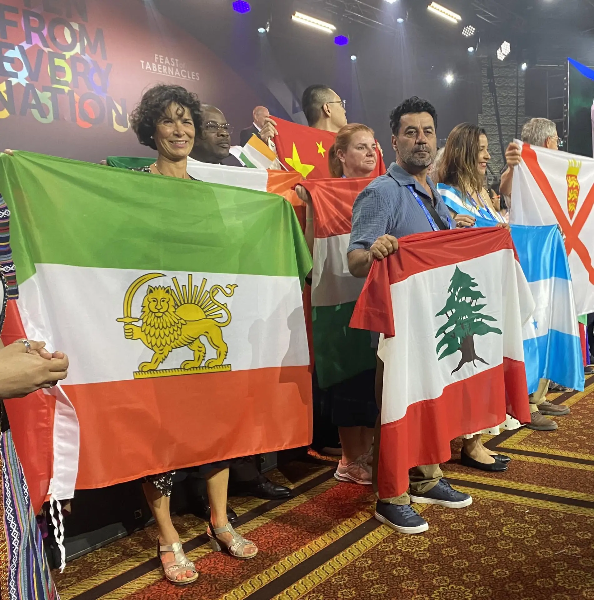 Bezoekers staan tijdens een bijeenkomst voor het Loofhuttenfeest met vlaggen van onder meer Iran, Libanon en Israël.